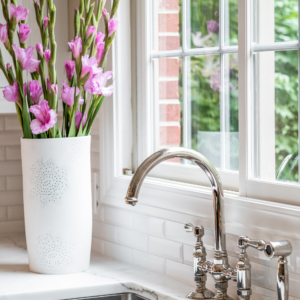 amberly-lane-sink Chrome faucet sitting over a kitchen sink next to flowers.